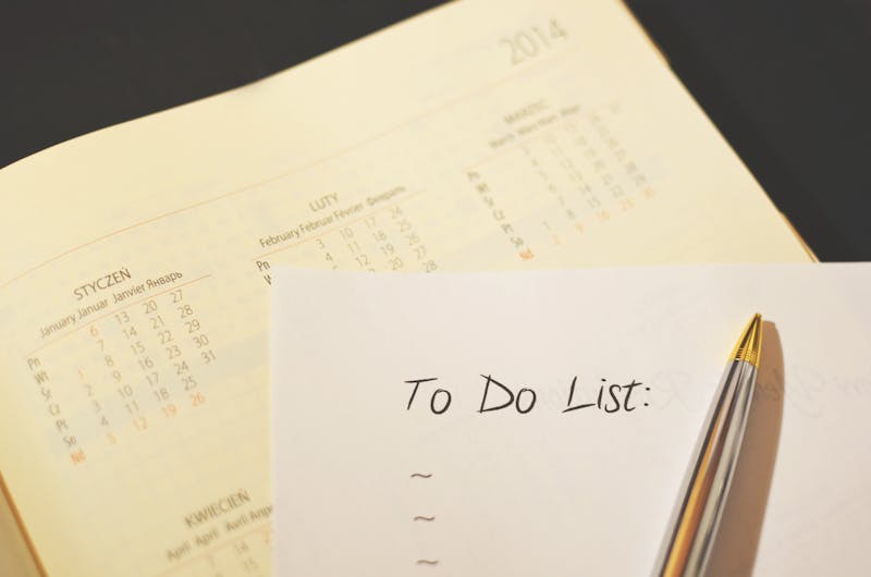 Close-up of a pen on a paper calendar with handwritten to-do checklist items